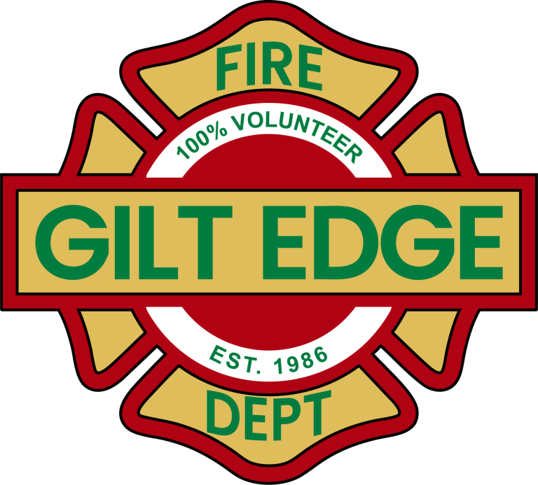 Logo of Gilt Edge Fire Department, featuring a red and gold badge with "GILT EDGE" in bold green letters across the center. It states "100% Volunteer" and "Est. 1986.